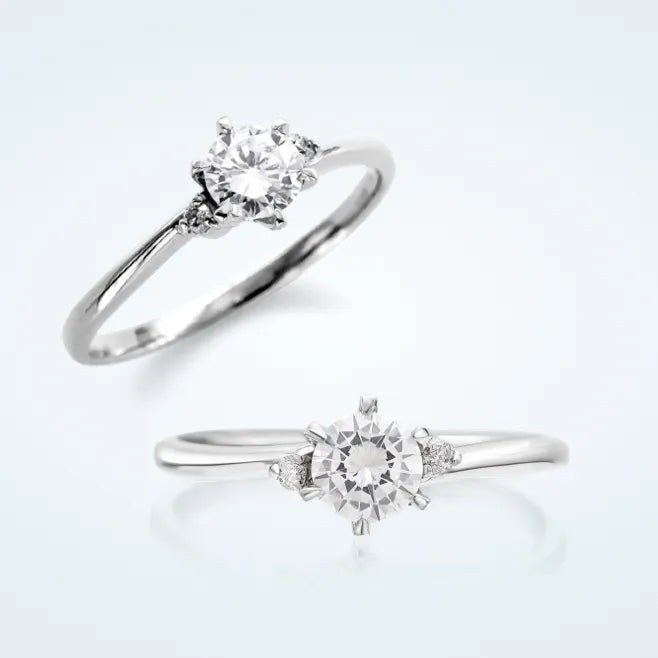 繊細でしなやかなウェーブラインに、センターの 0.3ct 天然ダイヤモンドを 6本爪で留めたエンゲージリングです。両サイドにメレダイヤモンド 2石（計0.04ct）を添えています。